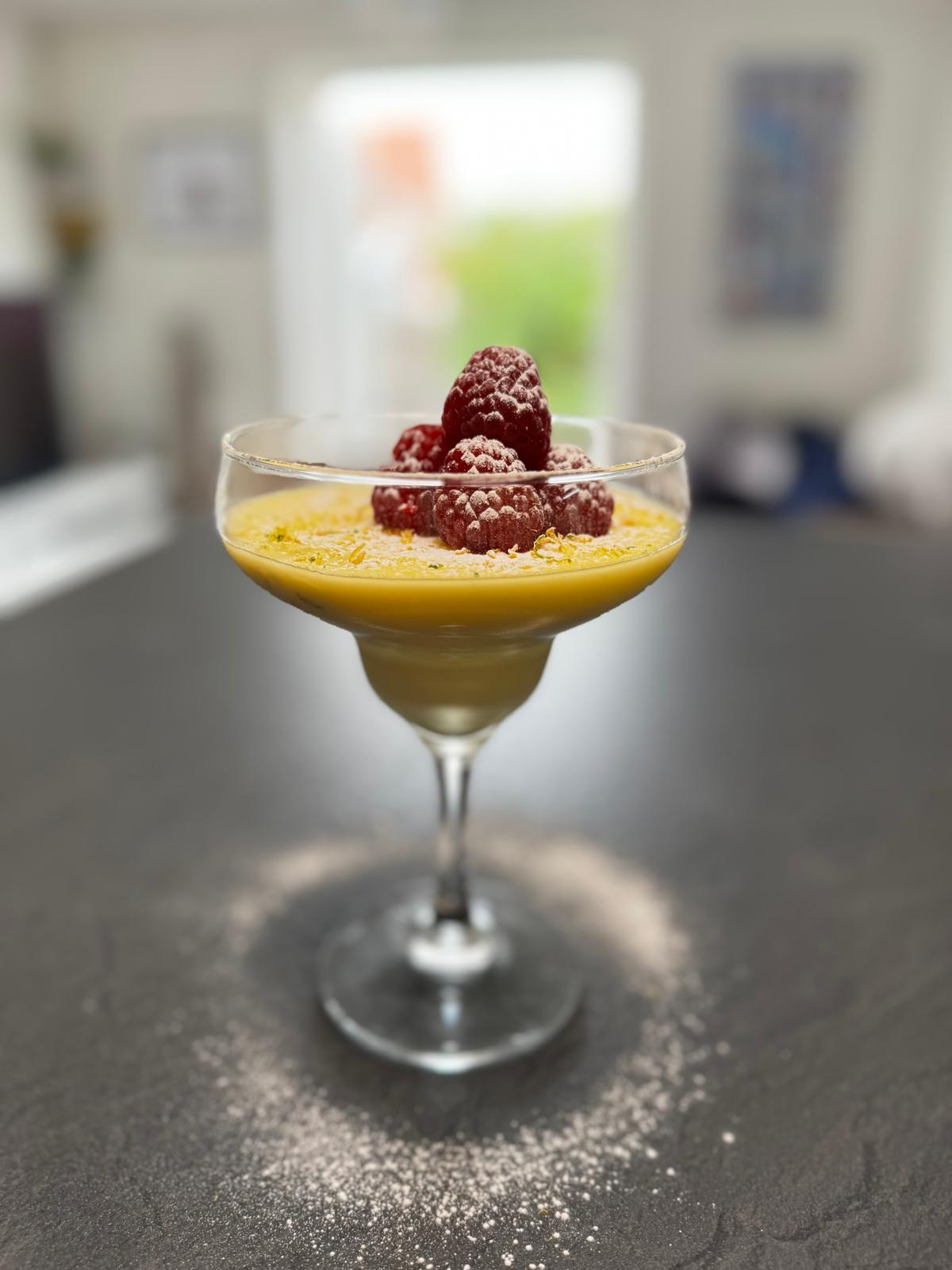 Lemon posset with raspberries in a coupe glass
